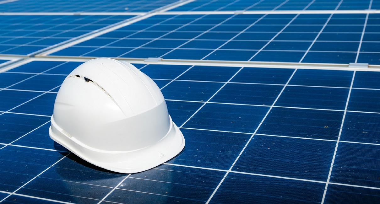 construction white hat on top of a solar panel