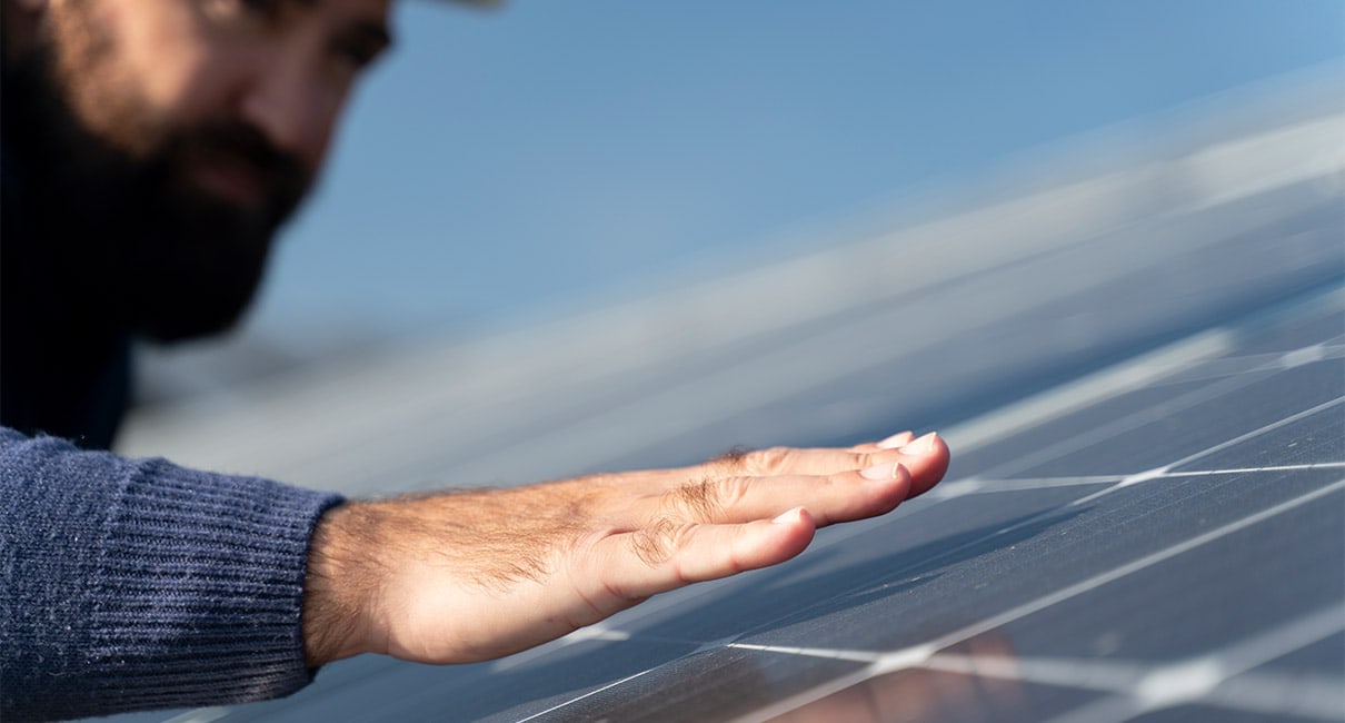 person looking and almost touching a solar panel